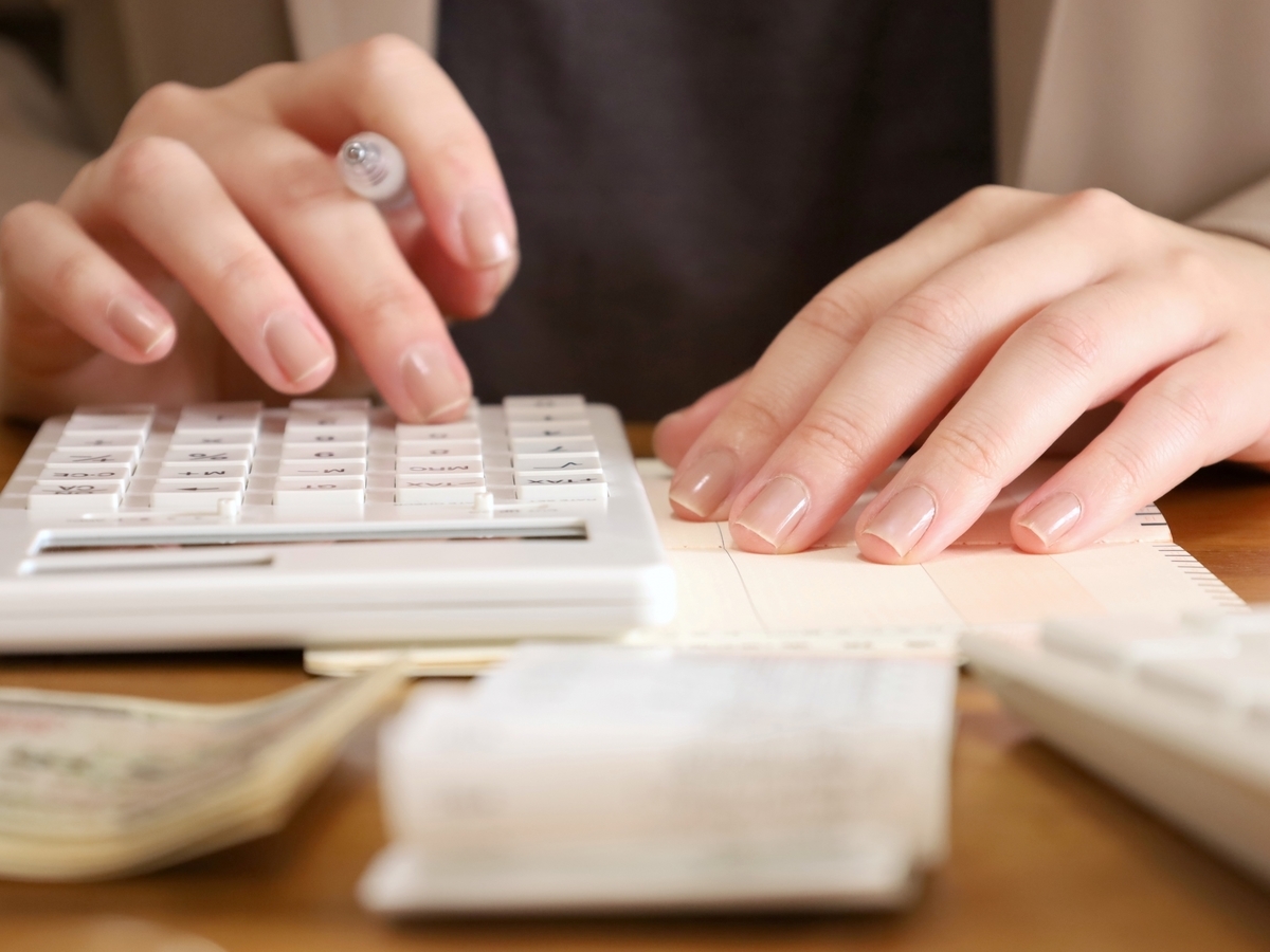 電卓で収支計算をする女性の手元