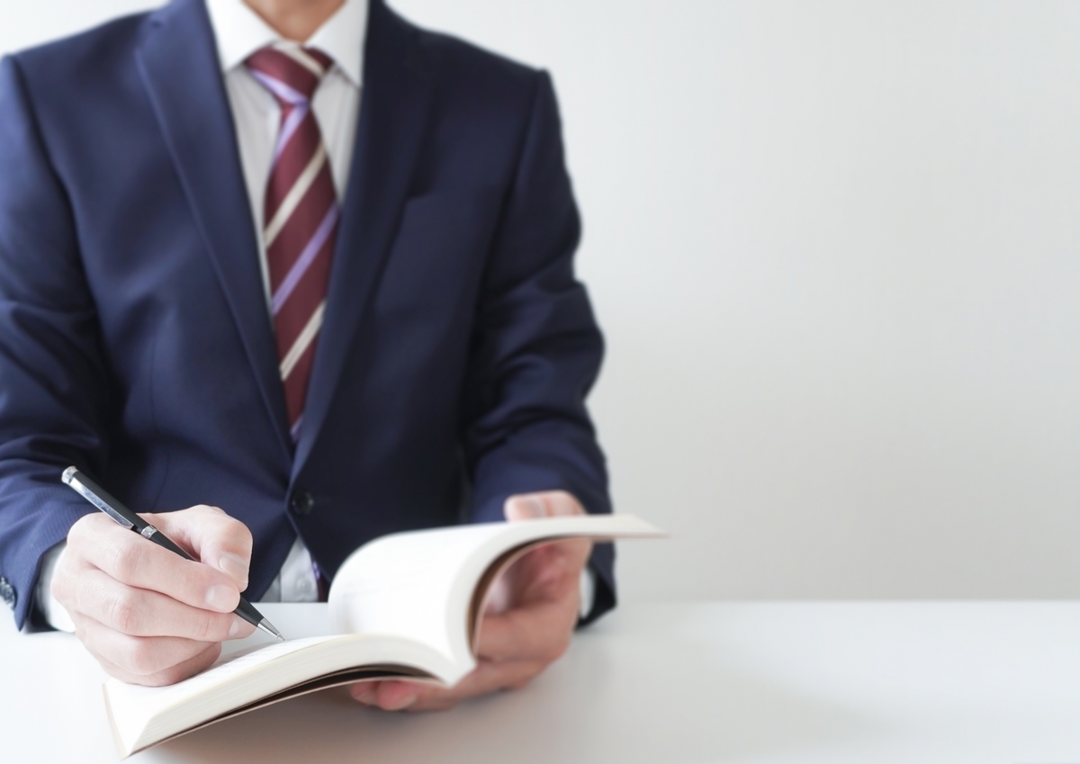 ノートに書き込むスーツの男性