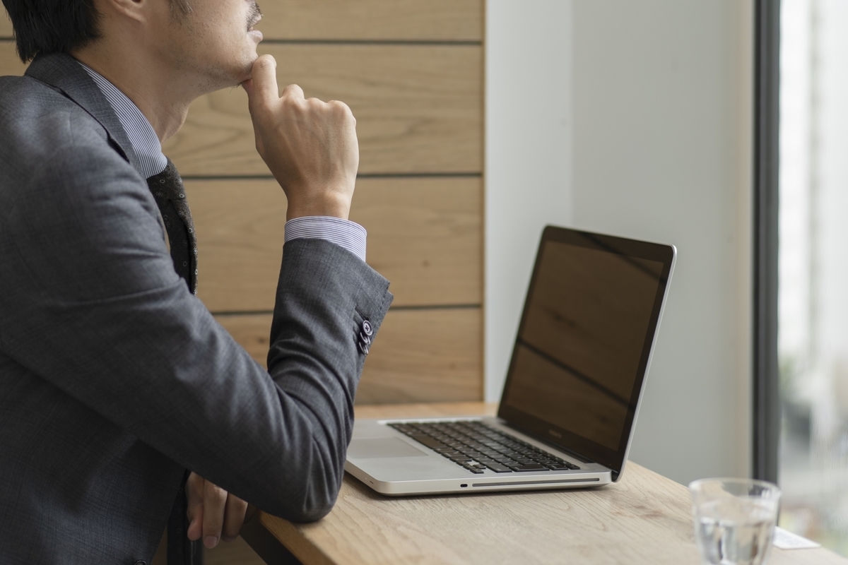 パソコンを前に何かを考える男性