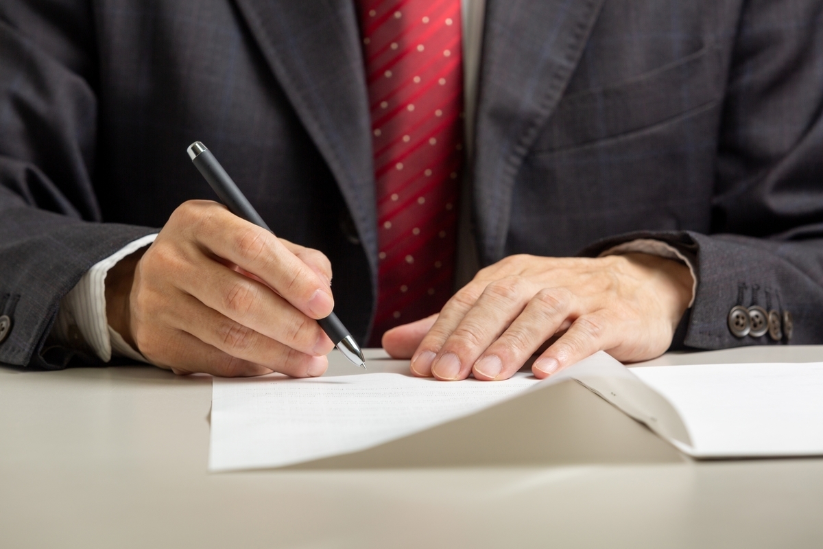 スーツで資料に記入する男性の手元