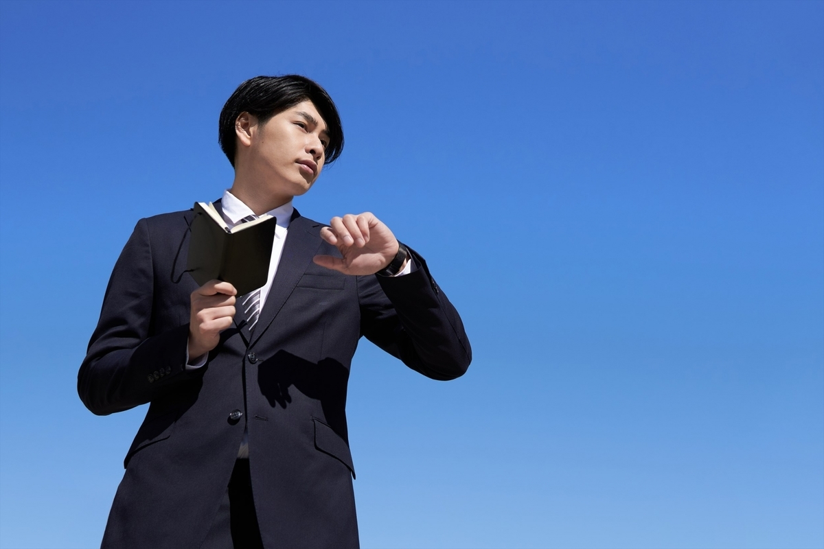 青空の下腕時計を見る男性