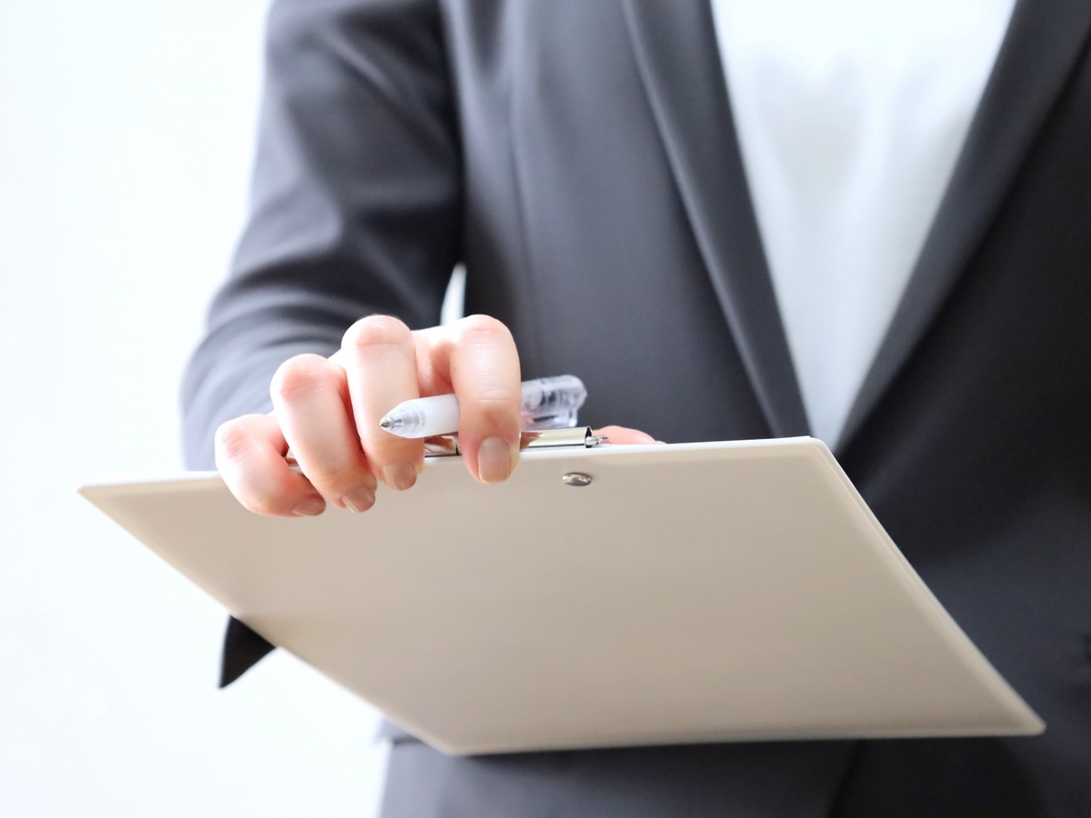 クリップボードとペンを持った人