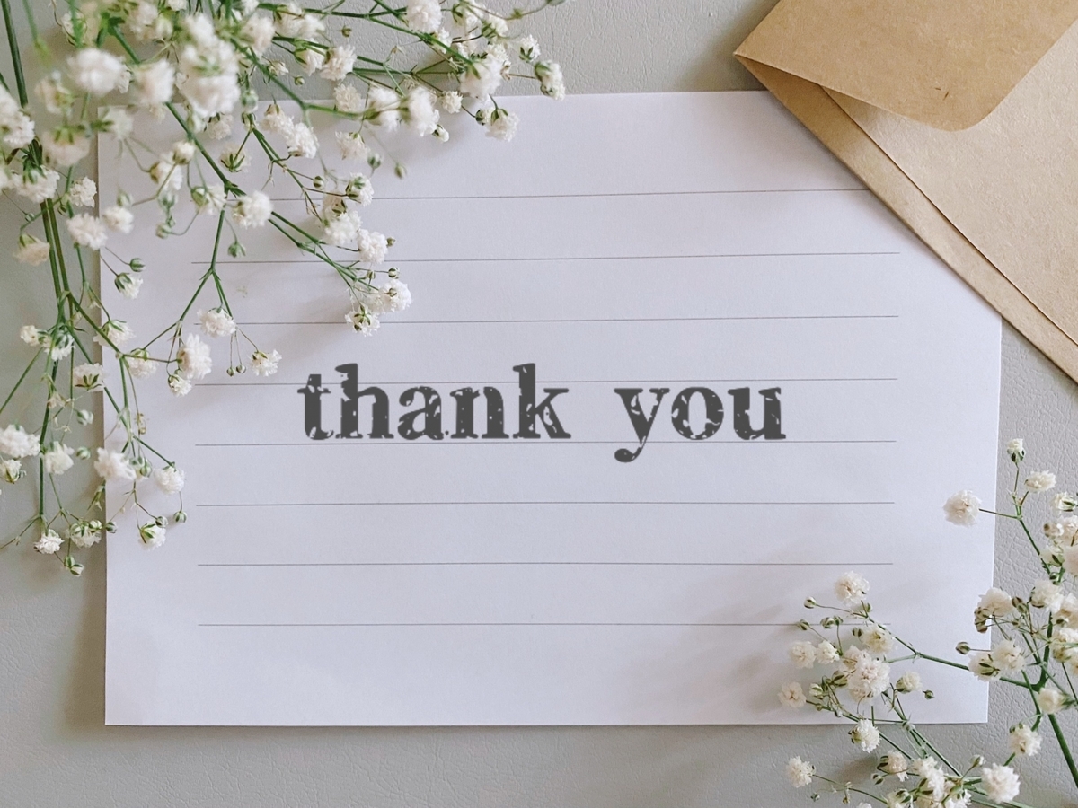 thank と書かれたメッセージカードと花と封筒