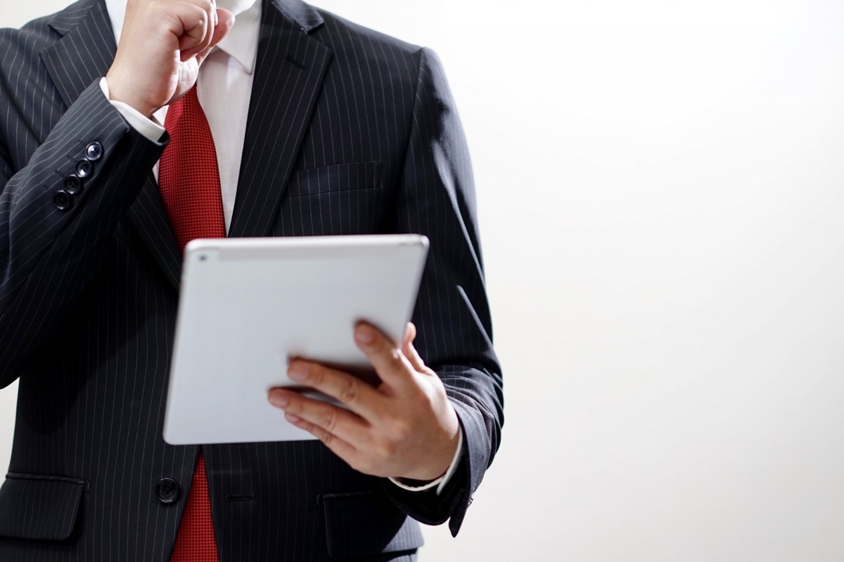 顎を触りながら電子機器を見る男性