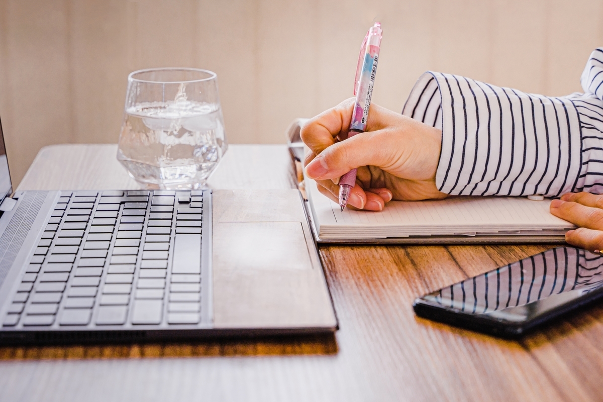 ノートパソコンとメモをとる人