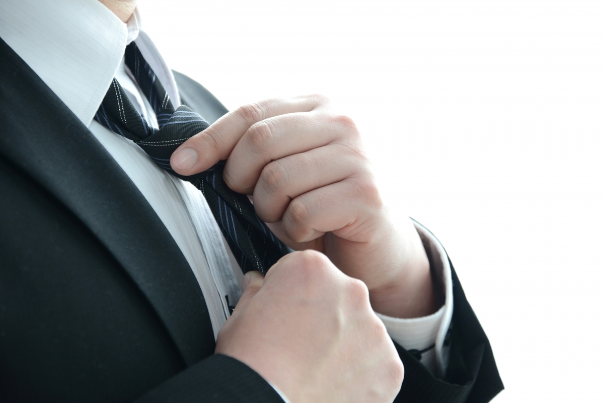 ネクタイを締めるスーツの男性