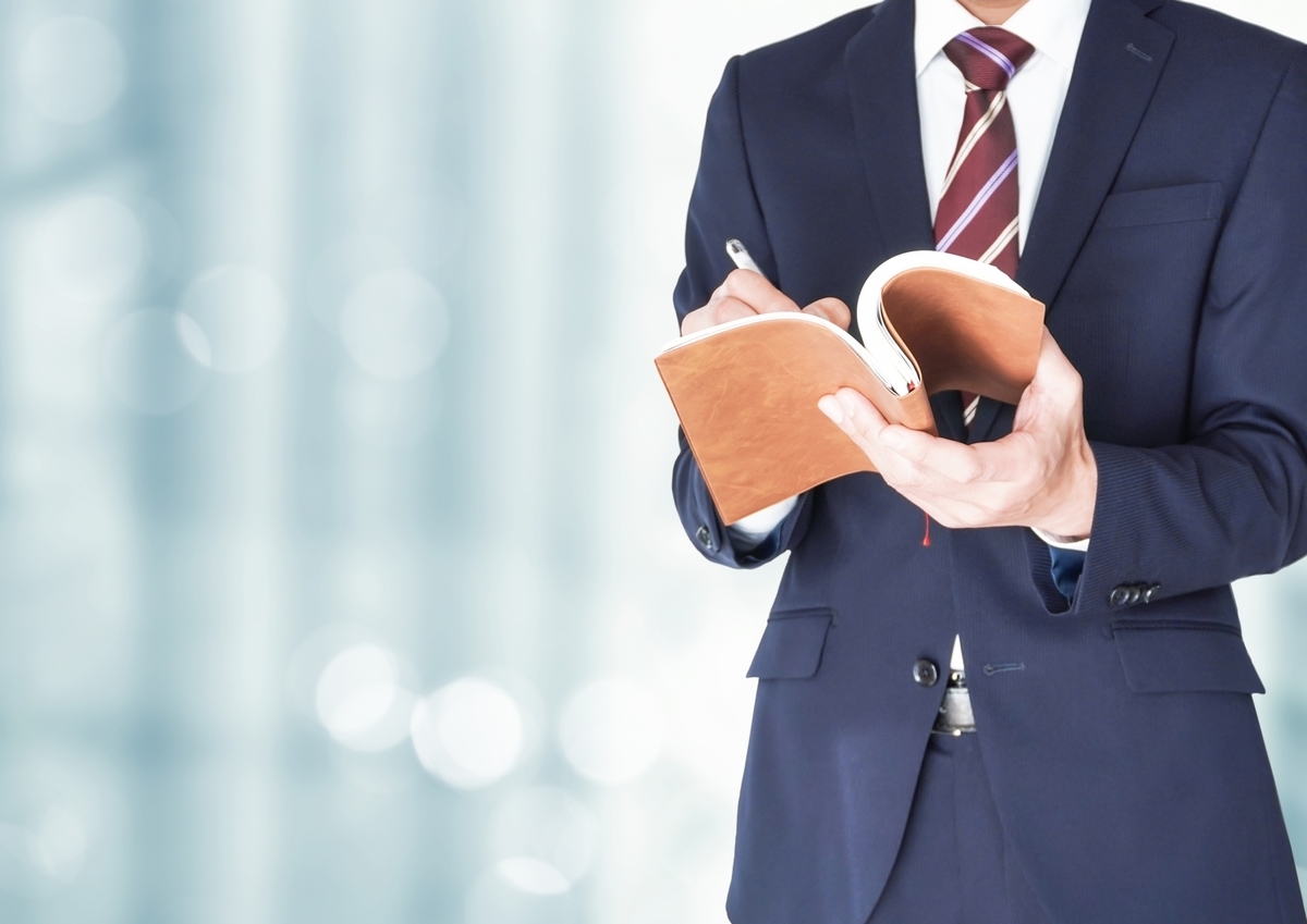 手帳に記入するスーツの男性