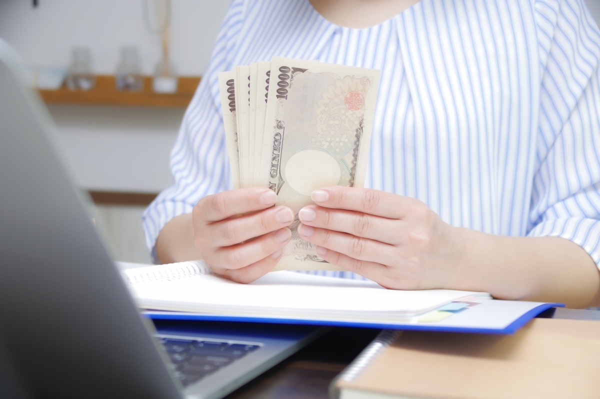 パソコンを前にお札を数える女性