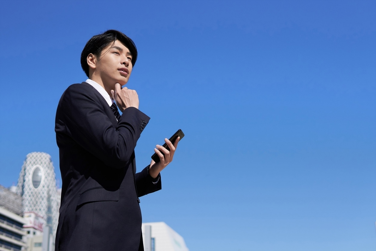 スマホを手に考え事をする男性