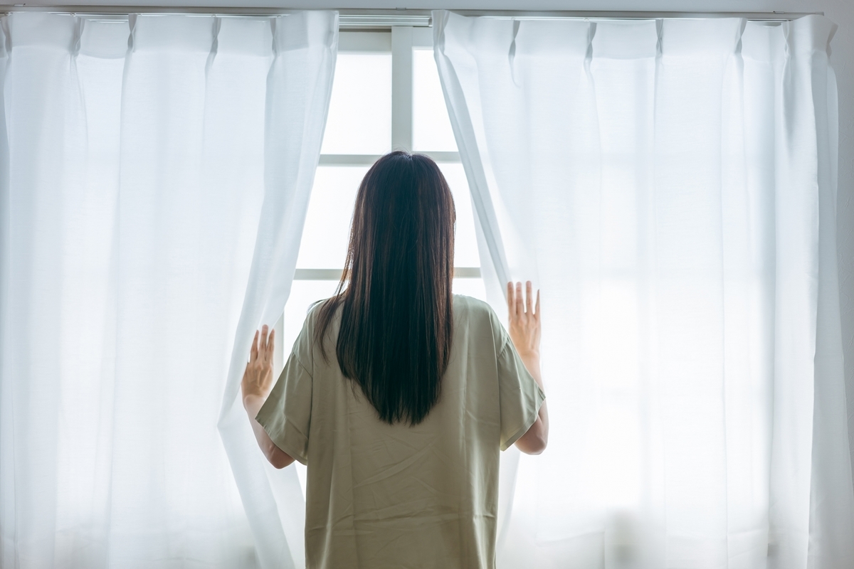 カーテンを開ける女性