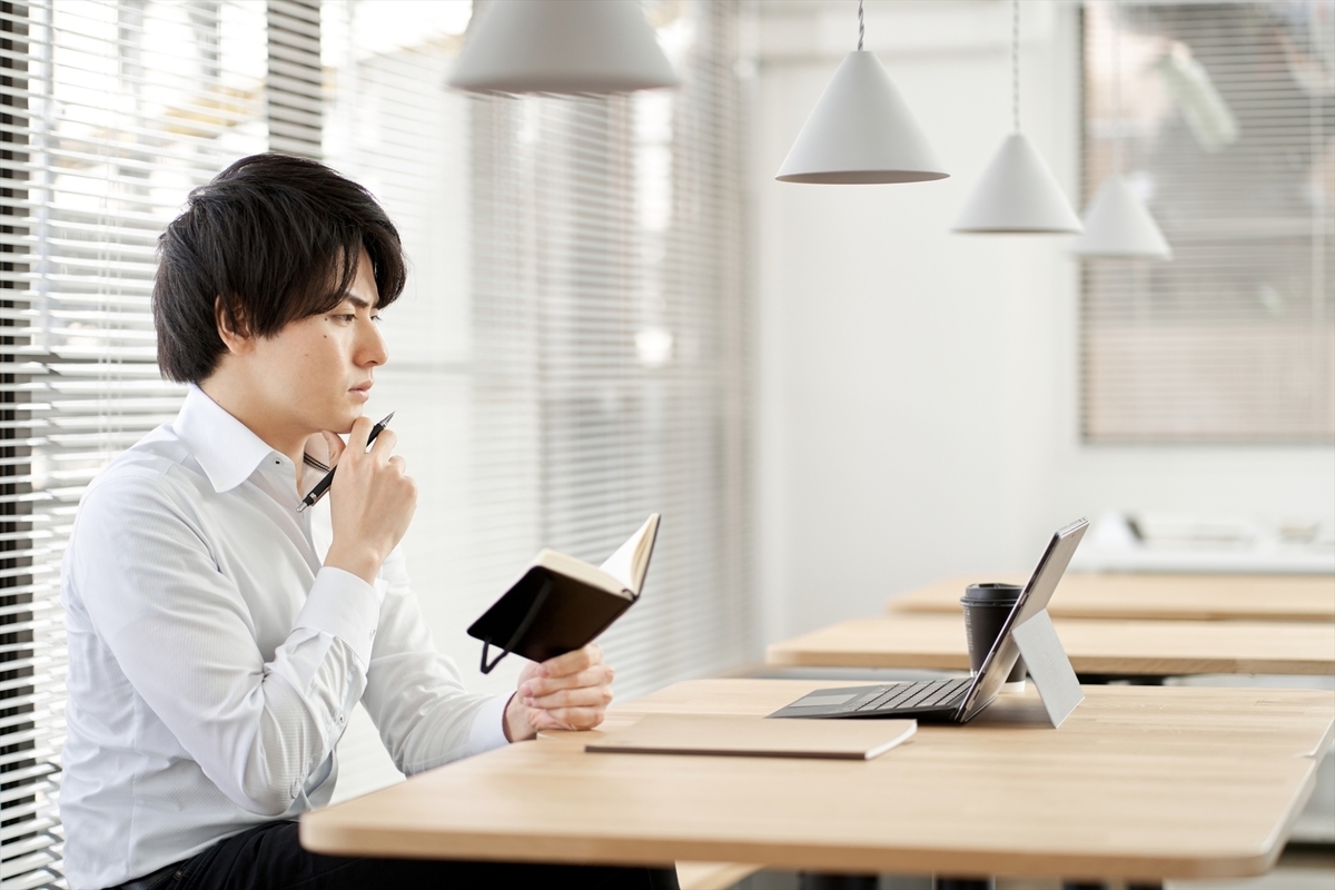 手帳を見ながら考える男性