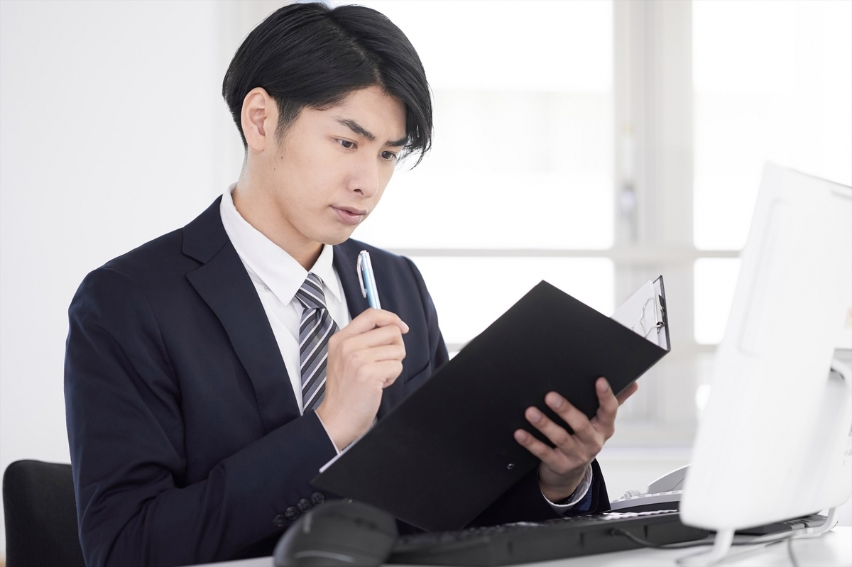 資料を手に考える男性