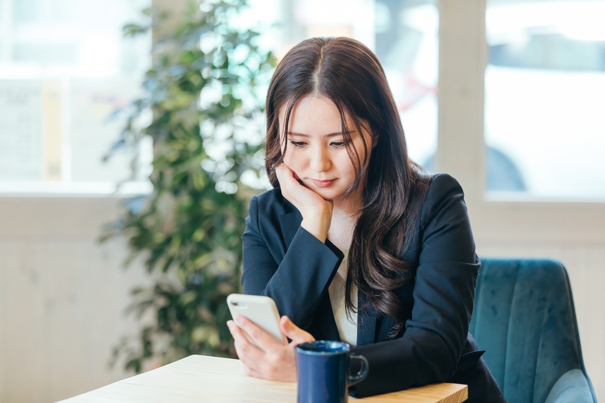 スマホを見て悩む女性