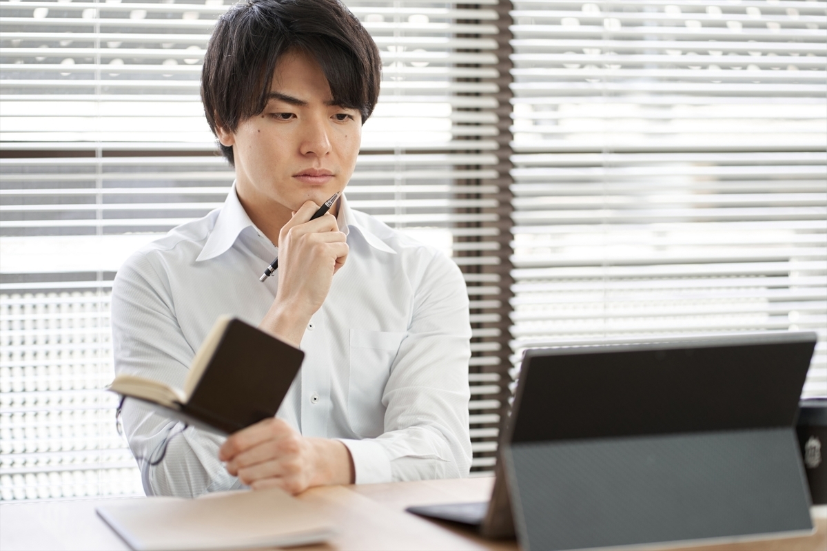 パソコンを前に考え事をする男性