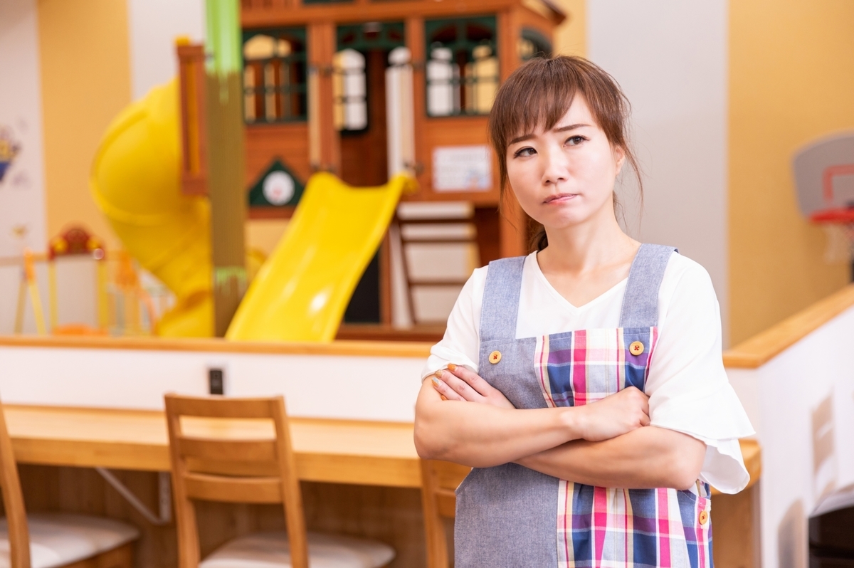 腕組みして考えている保育士
