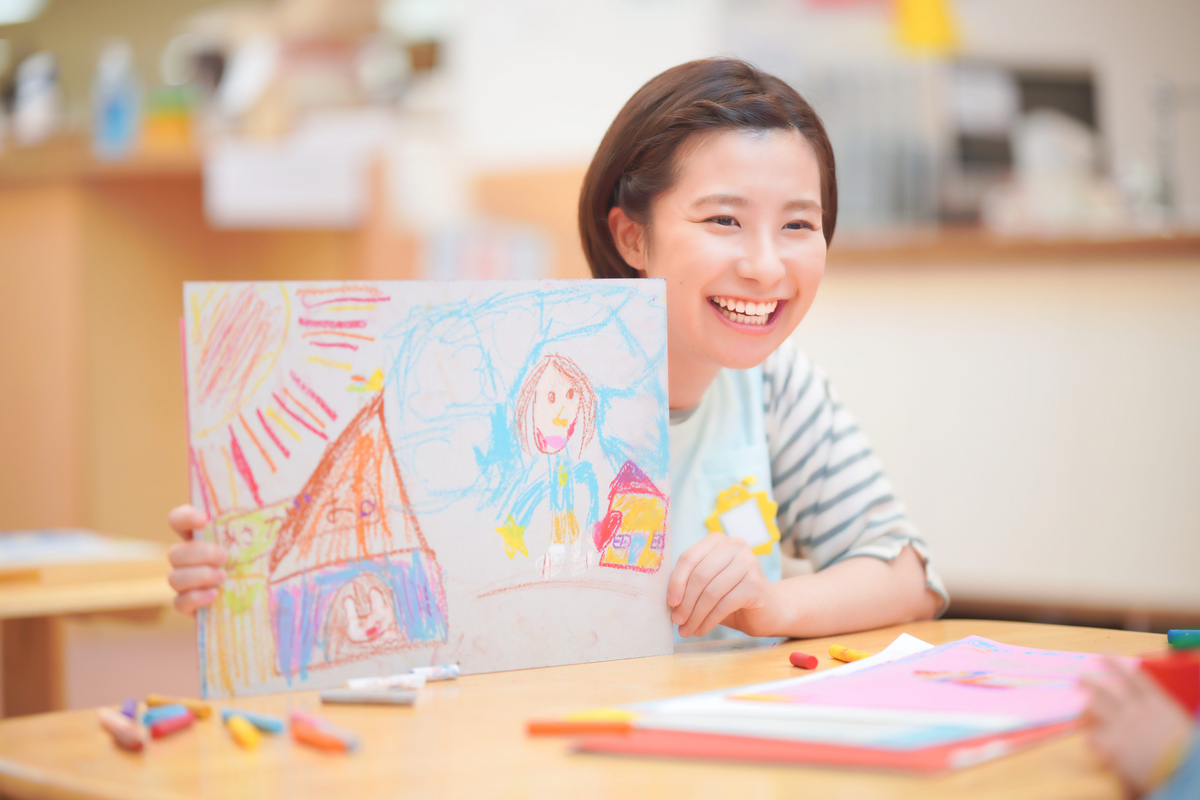 絵を見せている保育士の女性