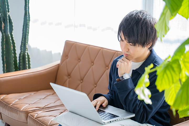 パソコンを見ながら考える男性