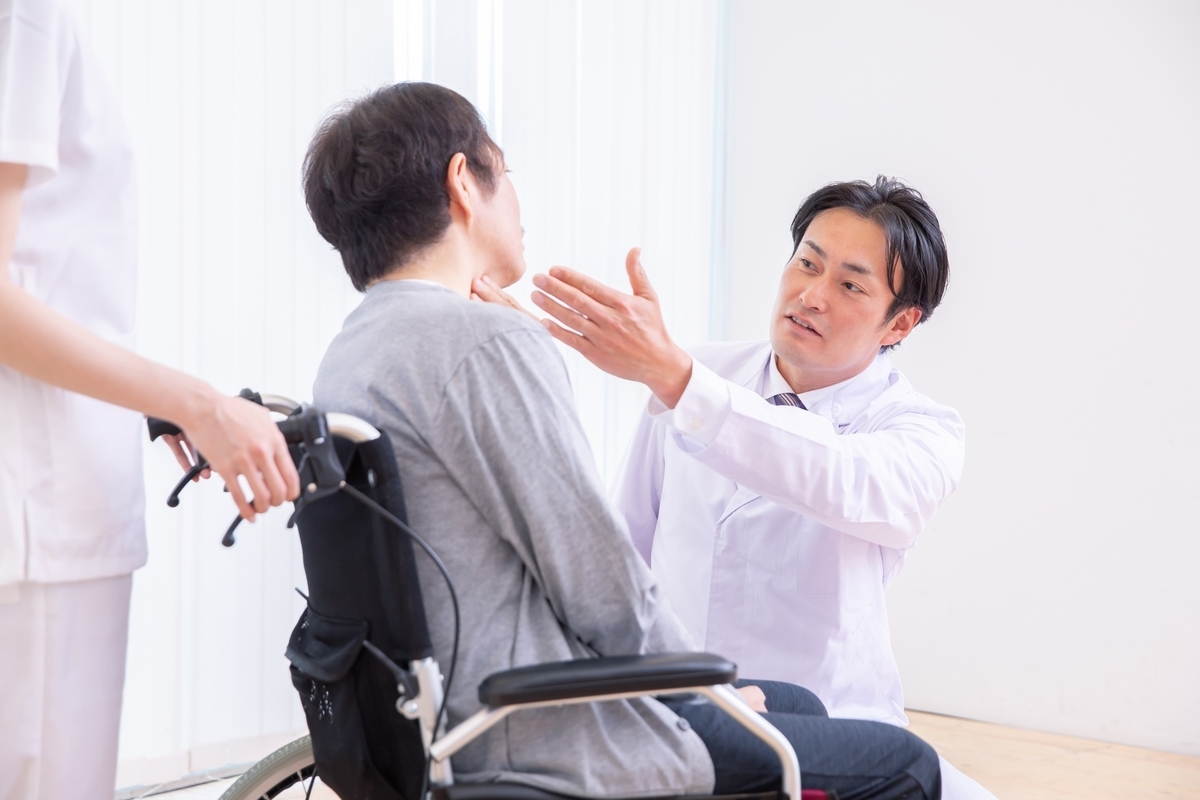 車いすの男性を触診する男性