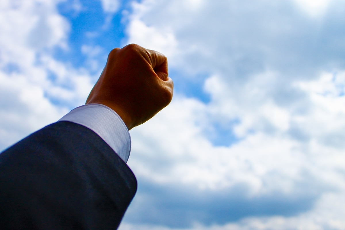 握った手を空に掲げる