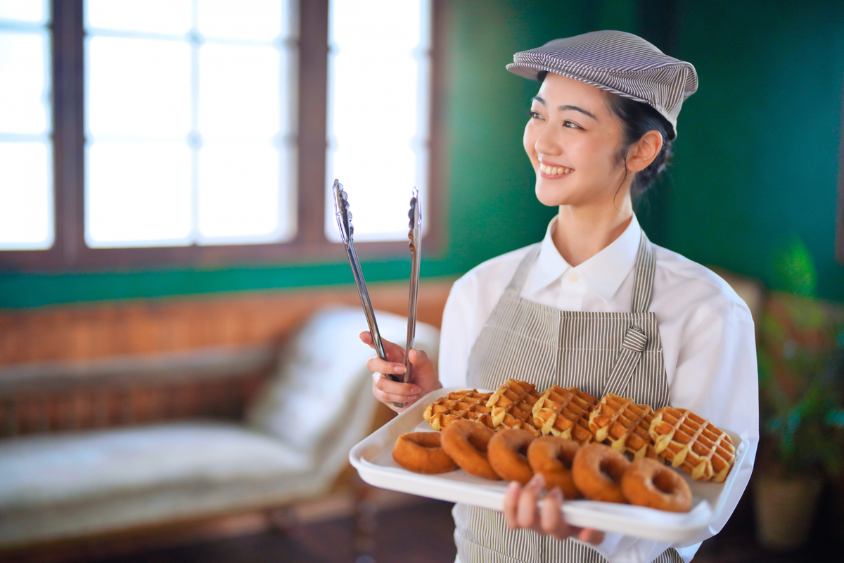 ドーナツを運ぶ女性のカフェスタッフ