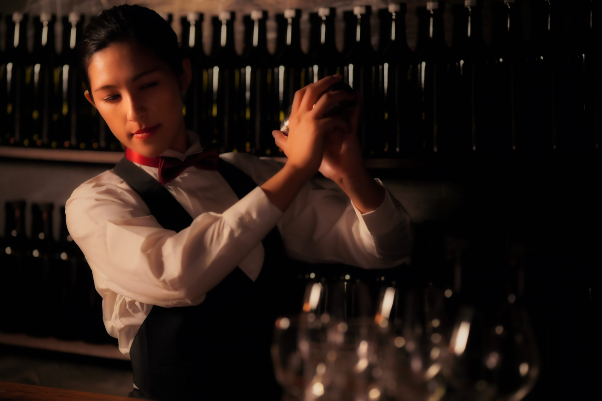 シェイカーを振るバーテンダーの女性