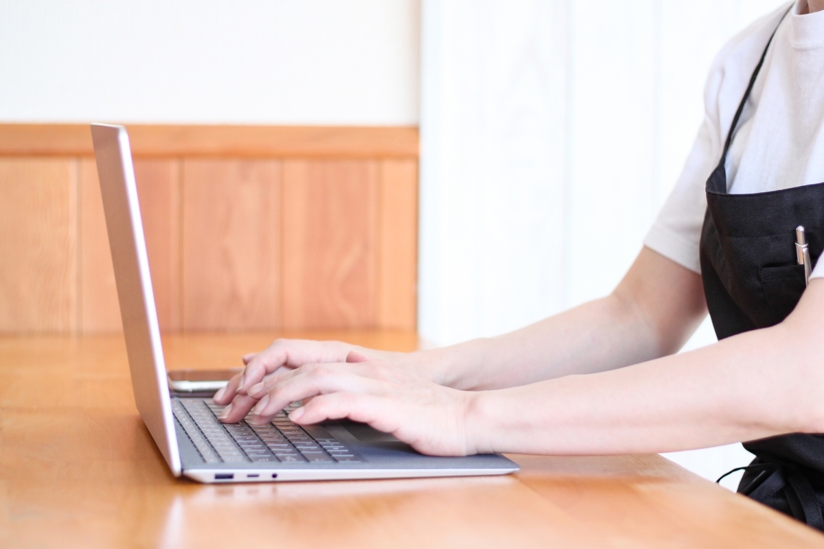 パソコンを触るエプロン姿の女性