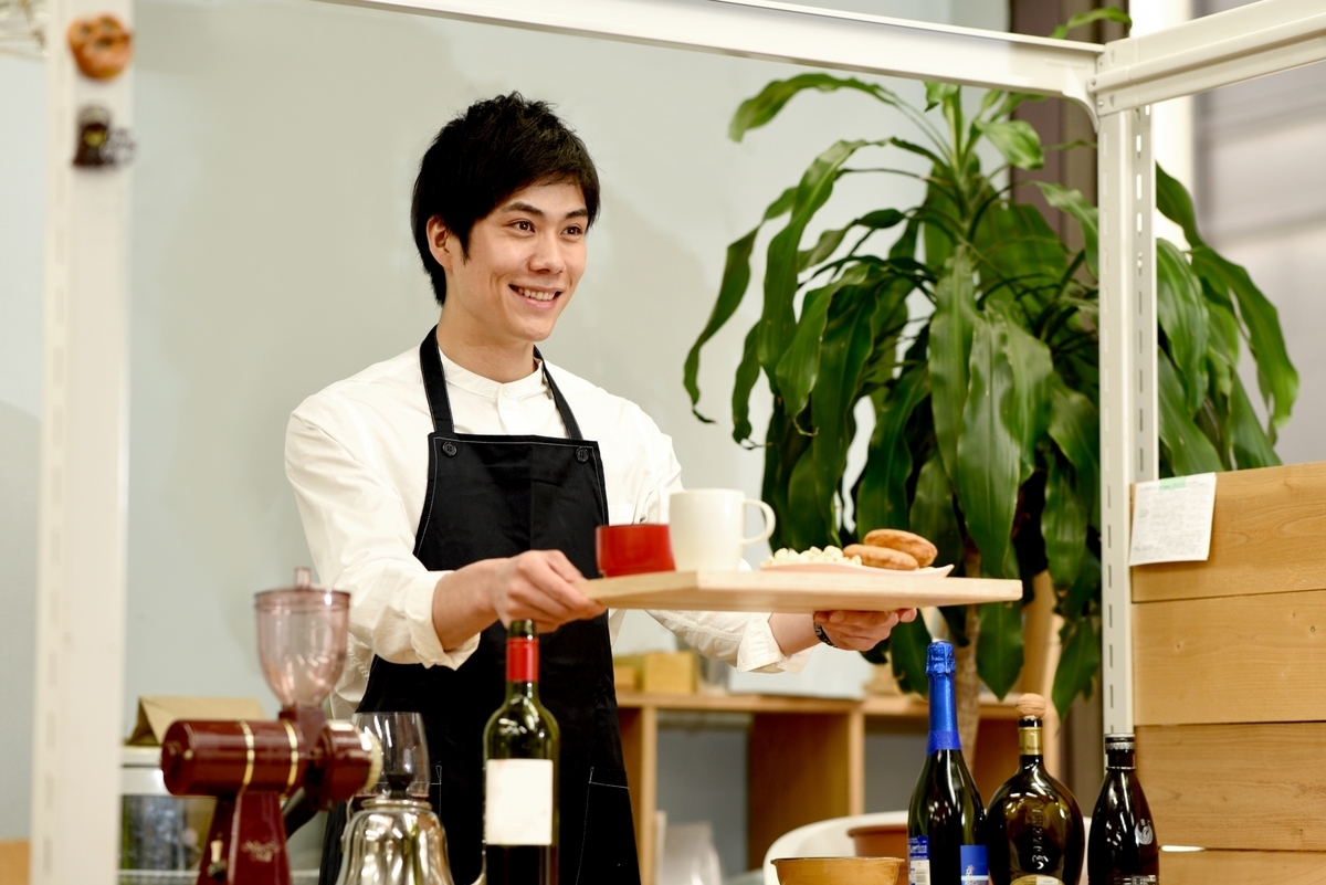 トレイを渡す男性スタッフ