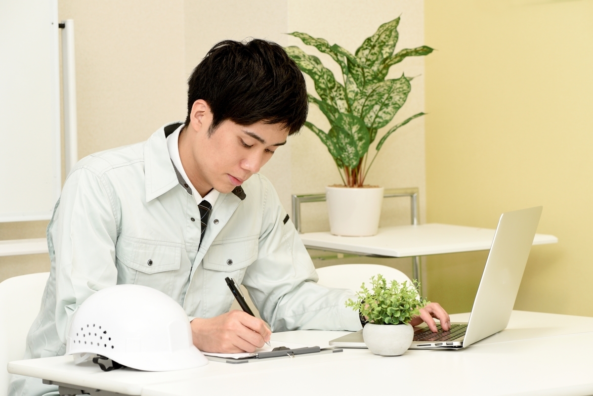 設計図を描く作業着の男性