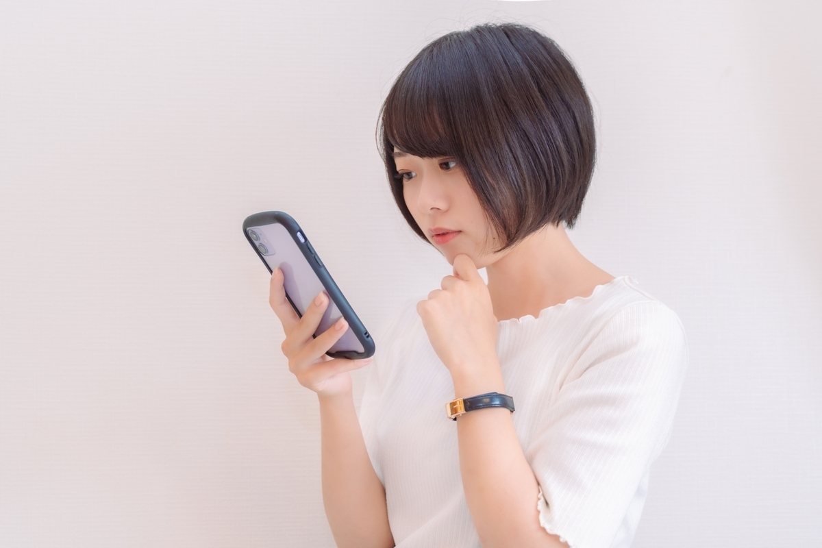 スマホを見て悩む女性