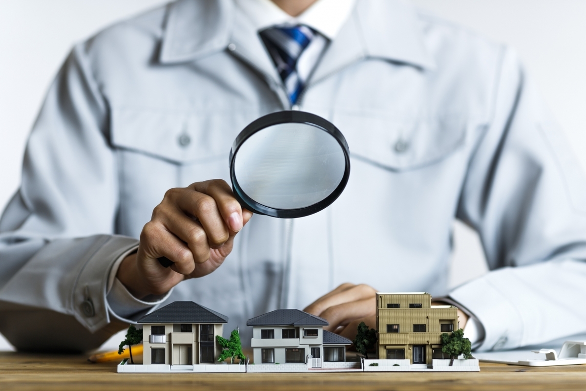 ルーペで住宅を観察する作業服の男性