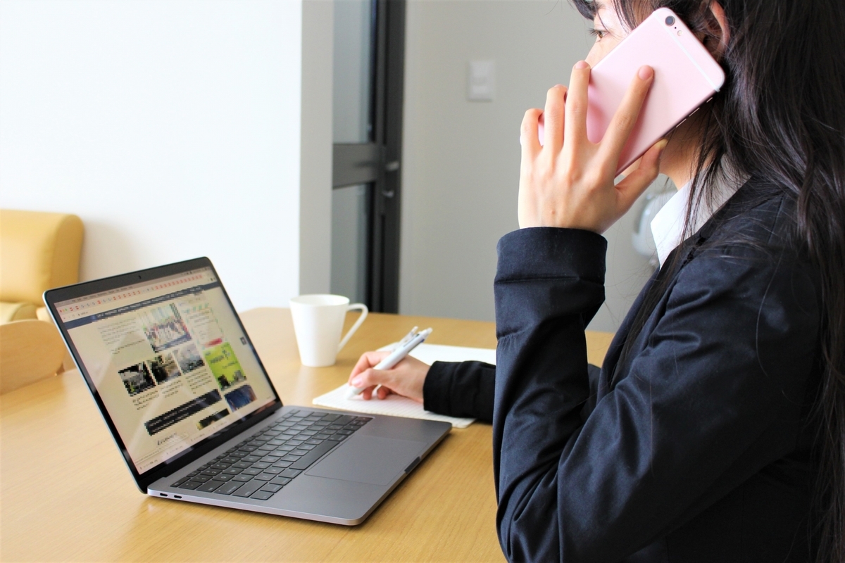 パソコンを操作しながら通話する女性