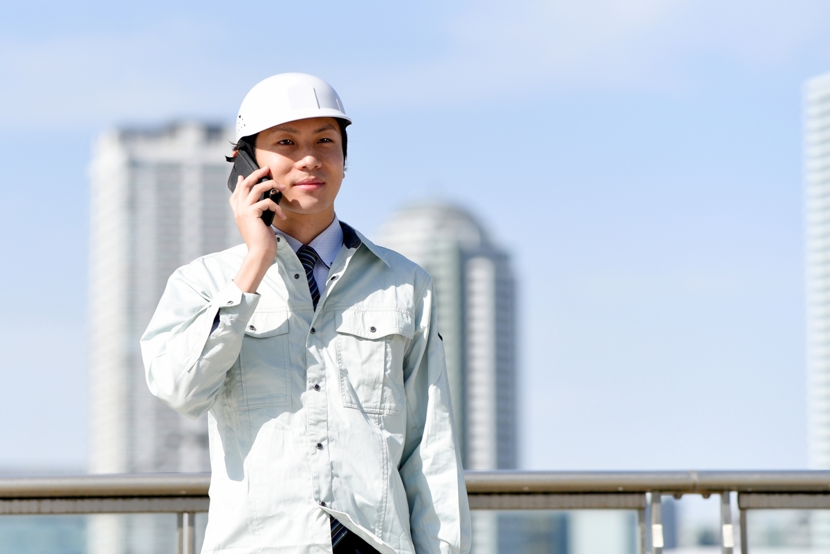 電話する作業着の男性