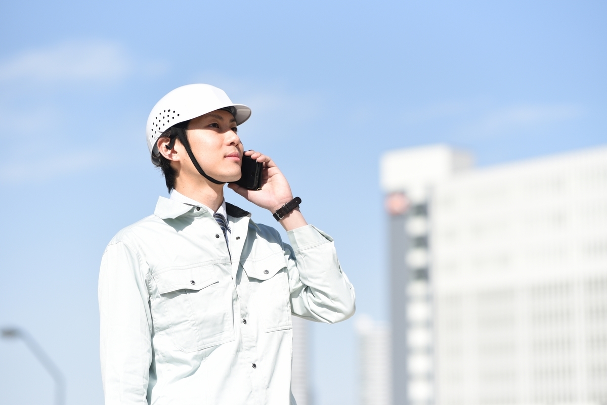 電話をする作業着の男性