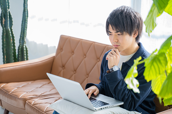 パソコンを見ながら考え事をする男性