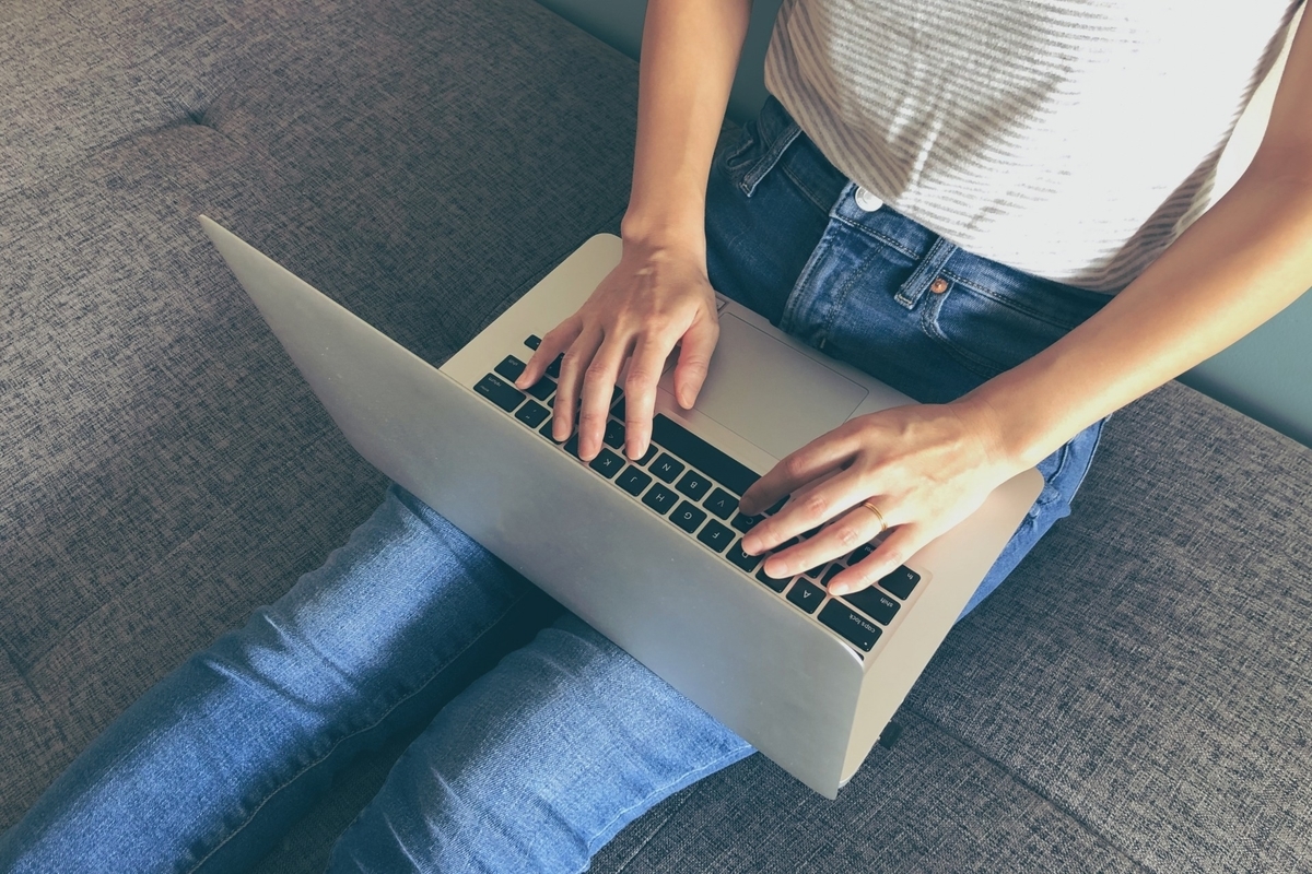 膝の上でパソコンを操作する女性