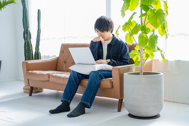 ソファに座ってパソコンを操作する男性