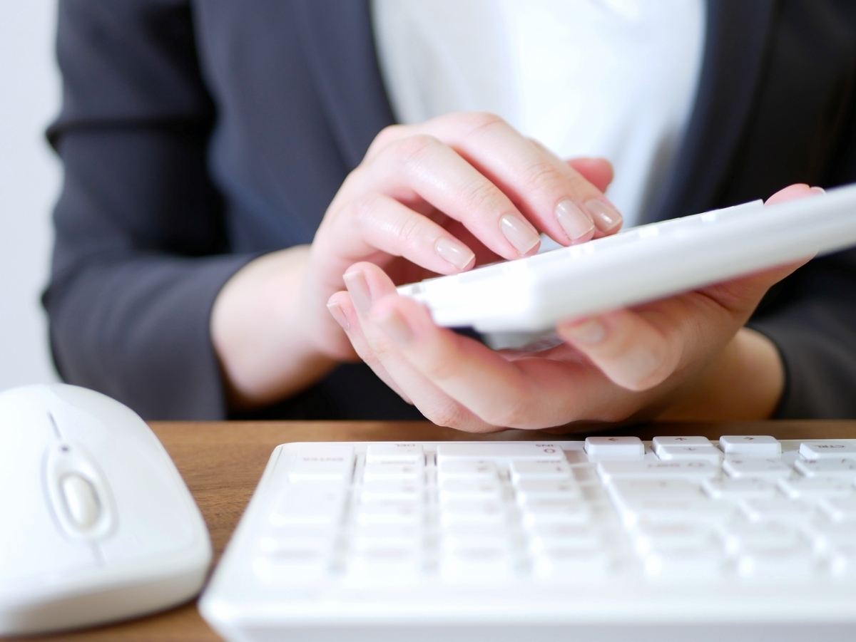 電卓を操作するスーツの女性