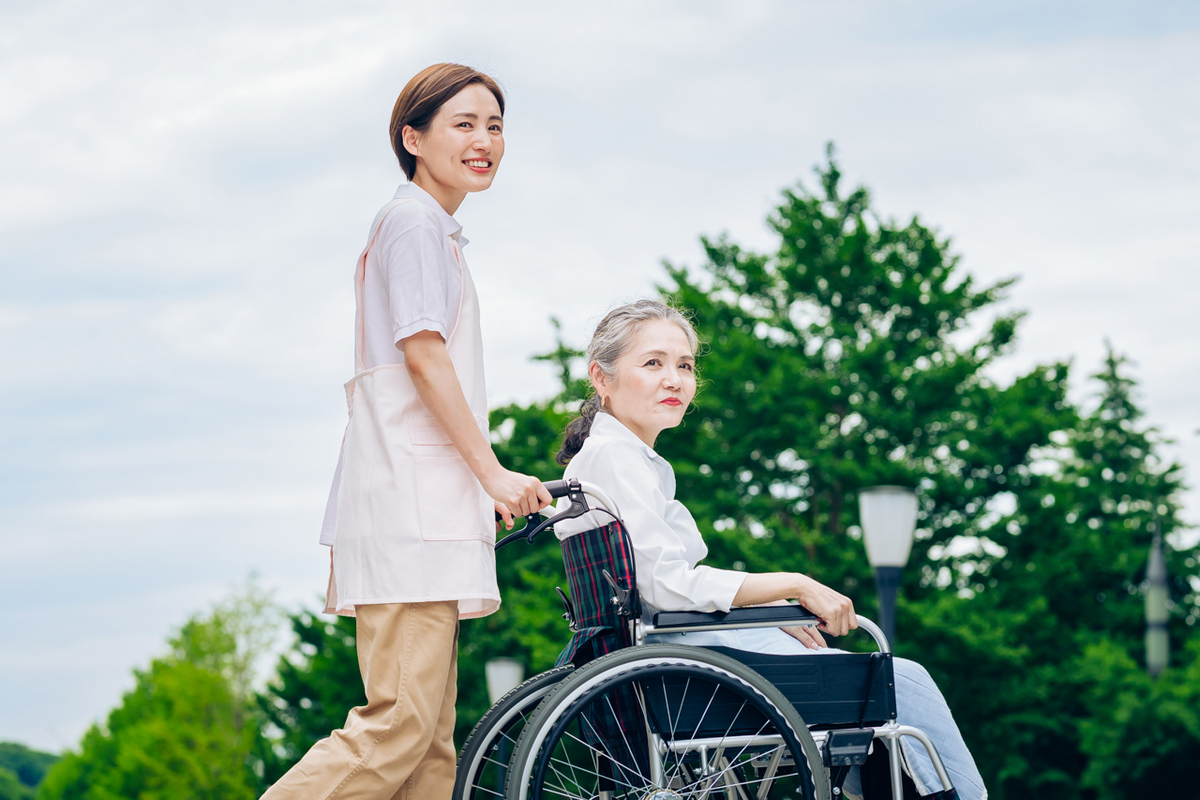 車いすを押すヘルパーの女性