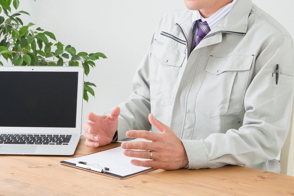 作業服で打ち合わせをする男性