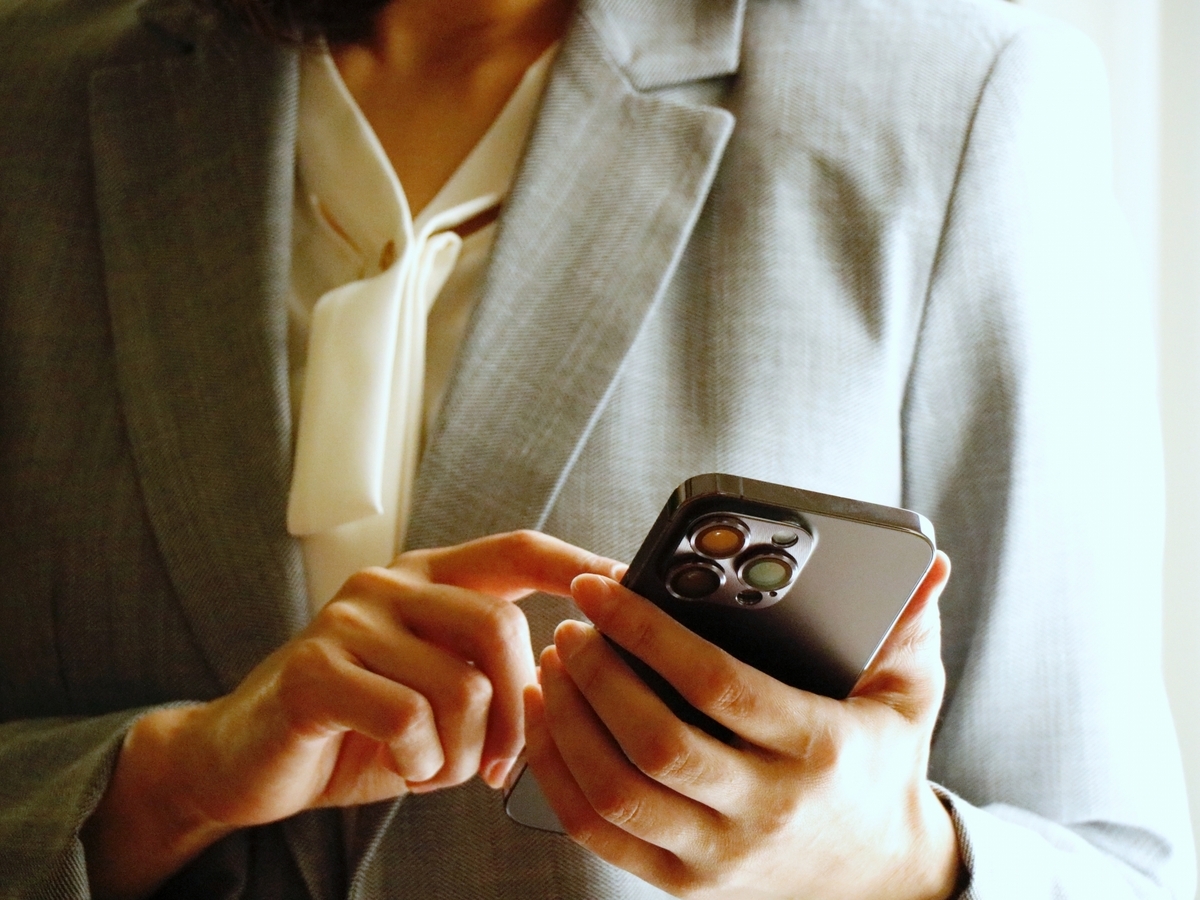 スマホを操作するスーツの女性