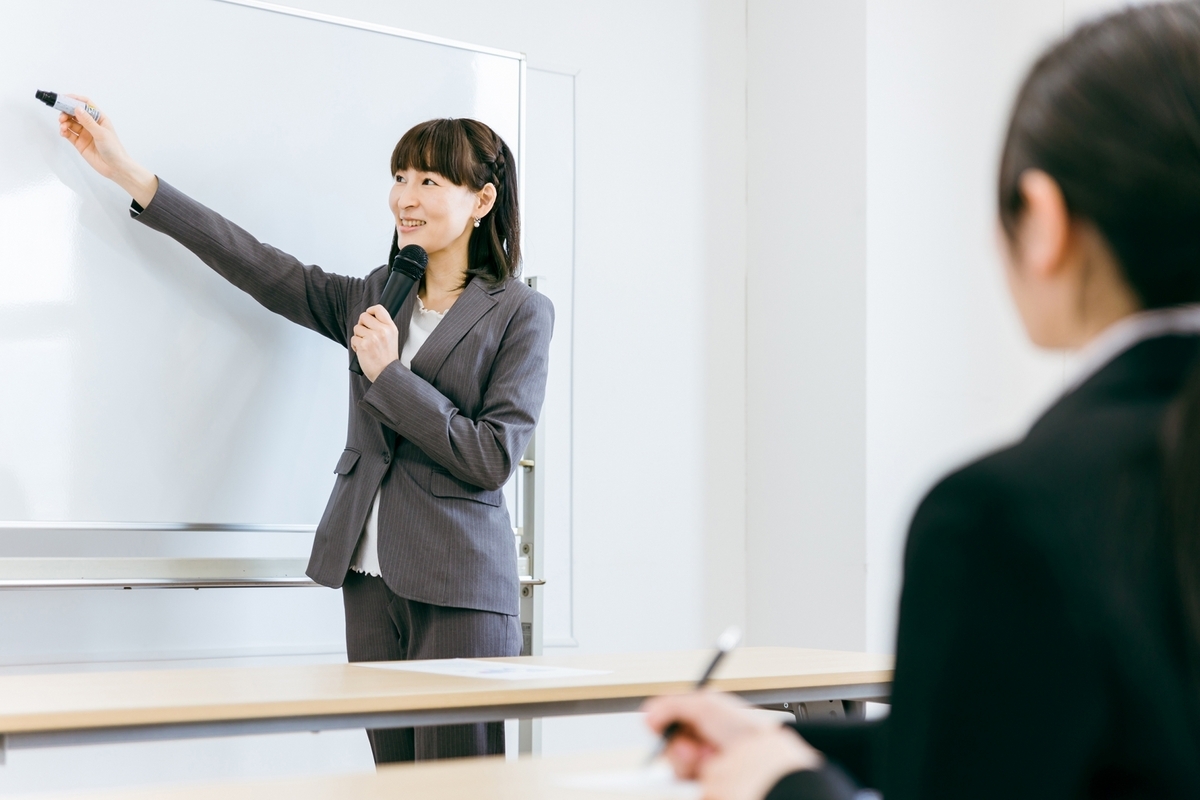 ホワイトボードに書き込む講師の女性