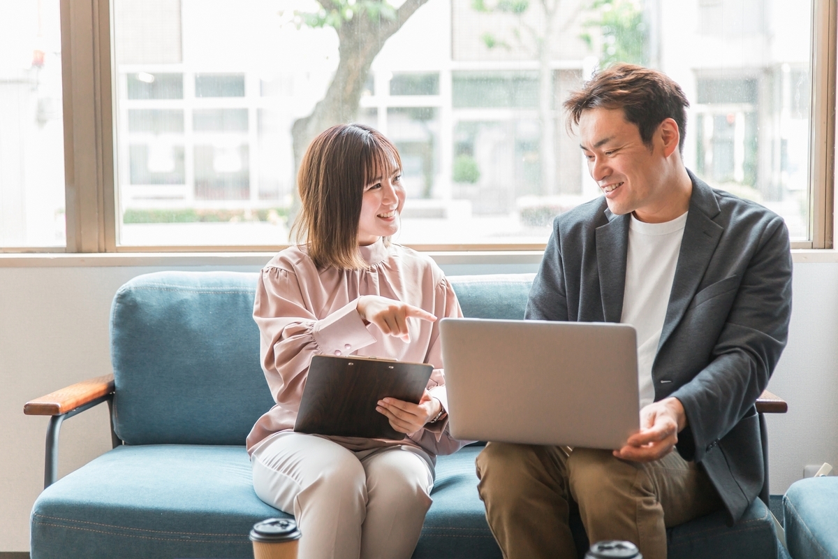 パソコンを持って打ち合わせをする二人