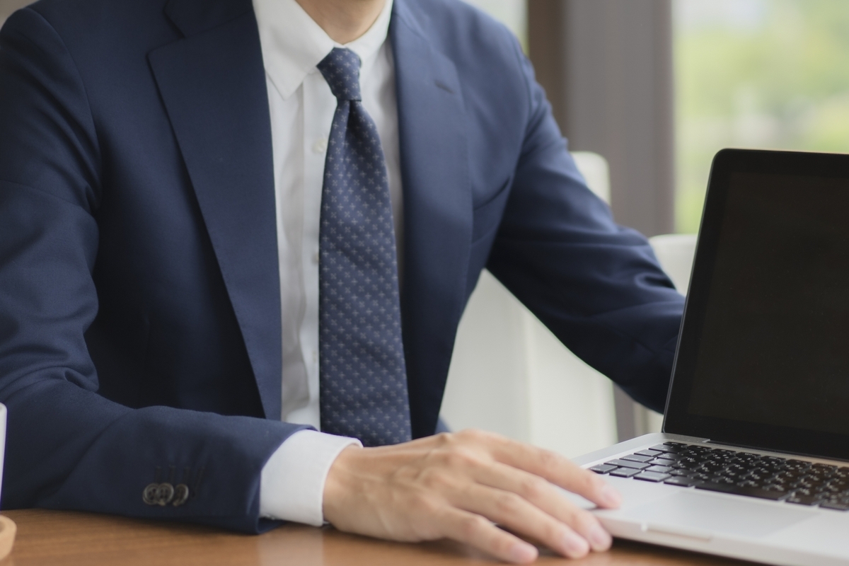 パソコンをデスクに置いているスーツの男性