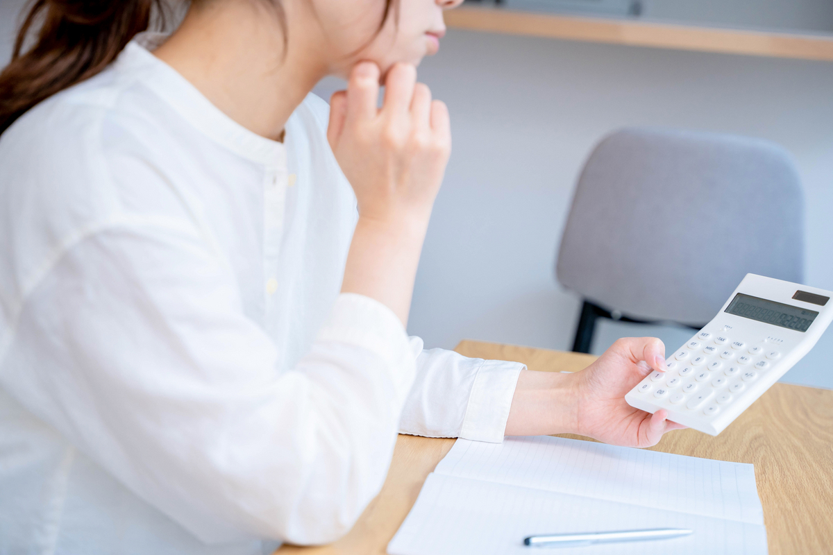 電卓を見ながら考える女性