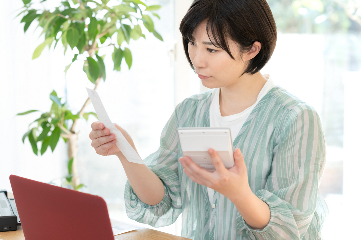 通帳と電卓を見る女性