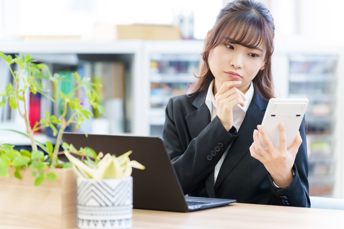 電卓を見ながら考える女性