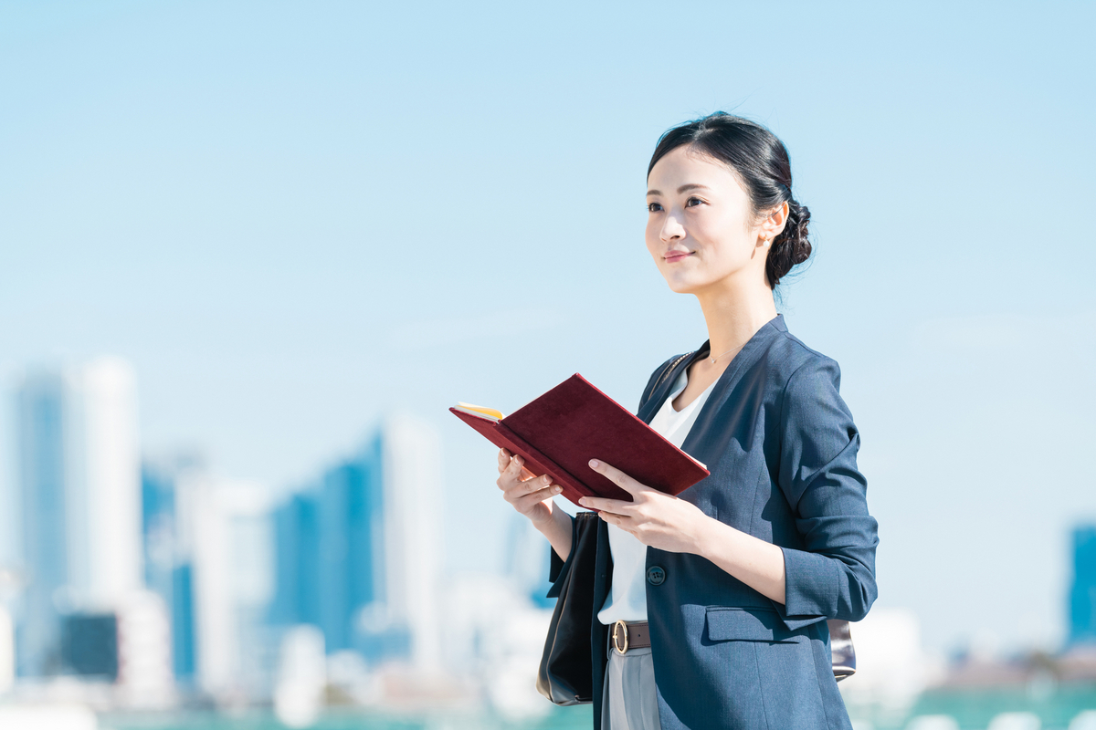 手帳を持った笑顔の女性ビジネスパーソン