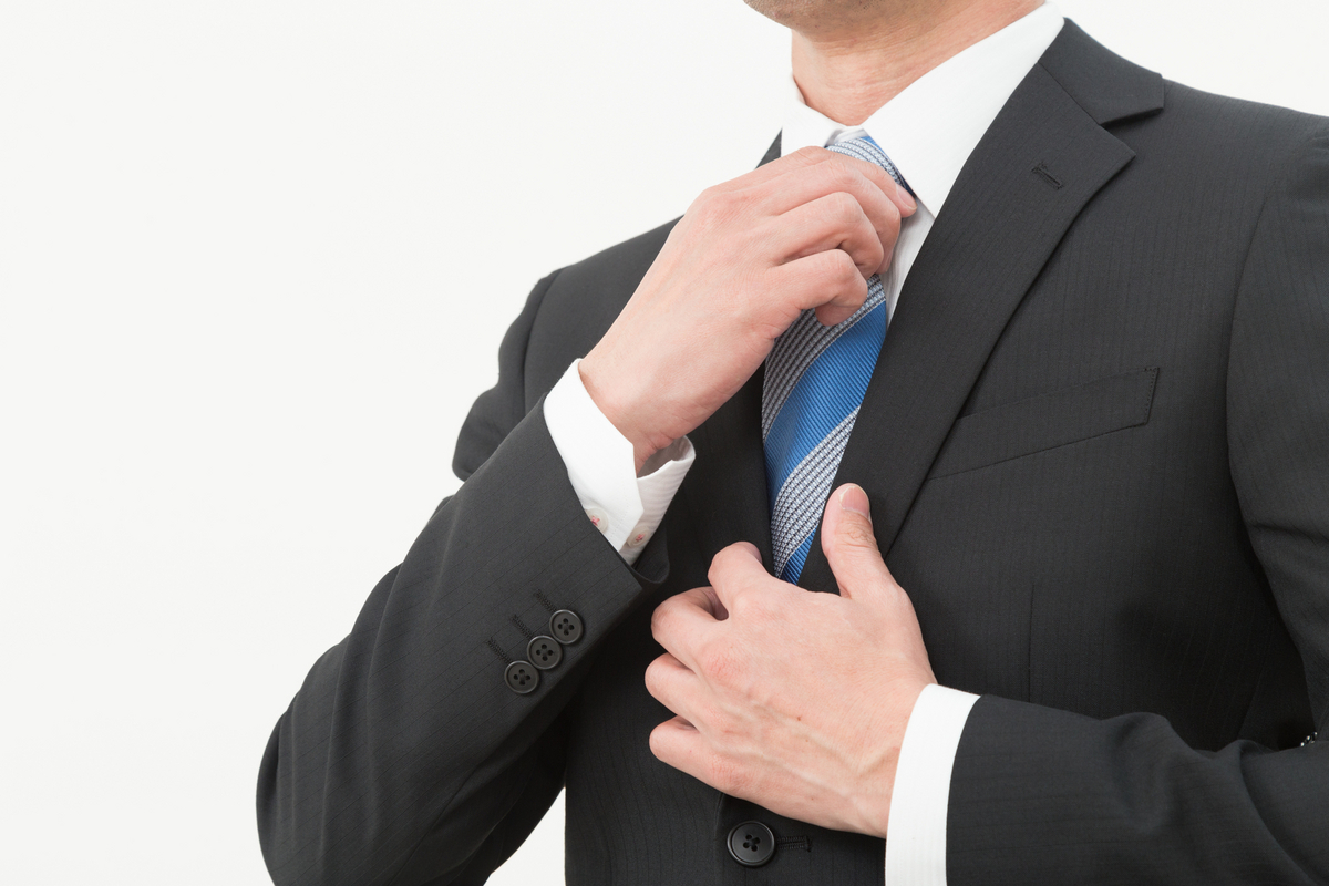 スーツのネクタイを整える男性