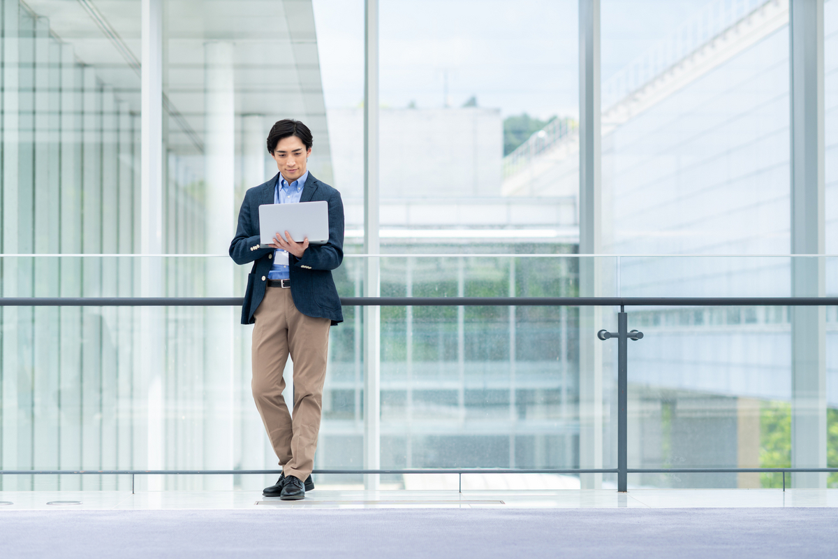パソコンを手に立っている男性