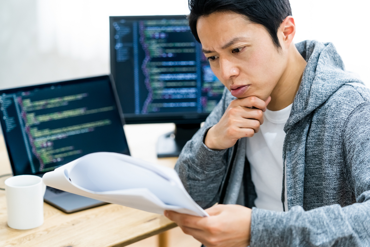 資料を見て考え込むプログラマー